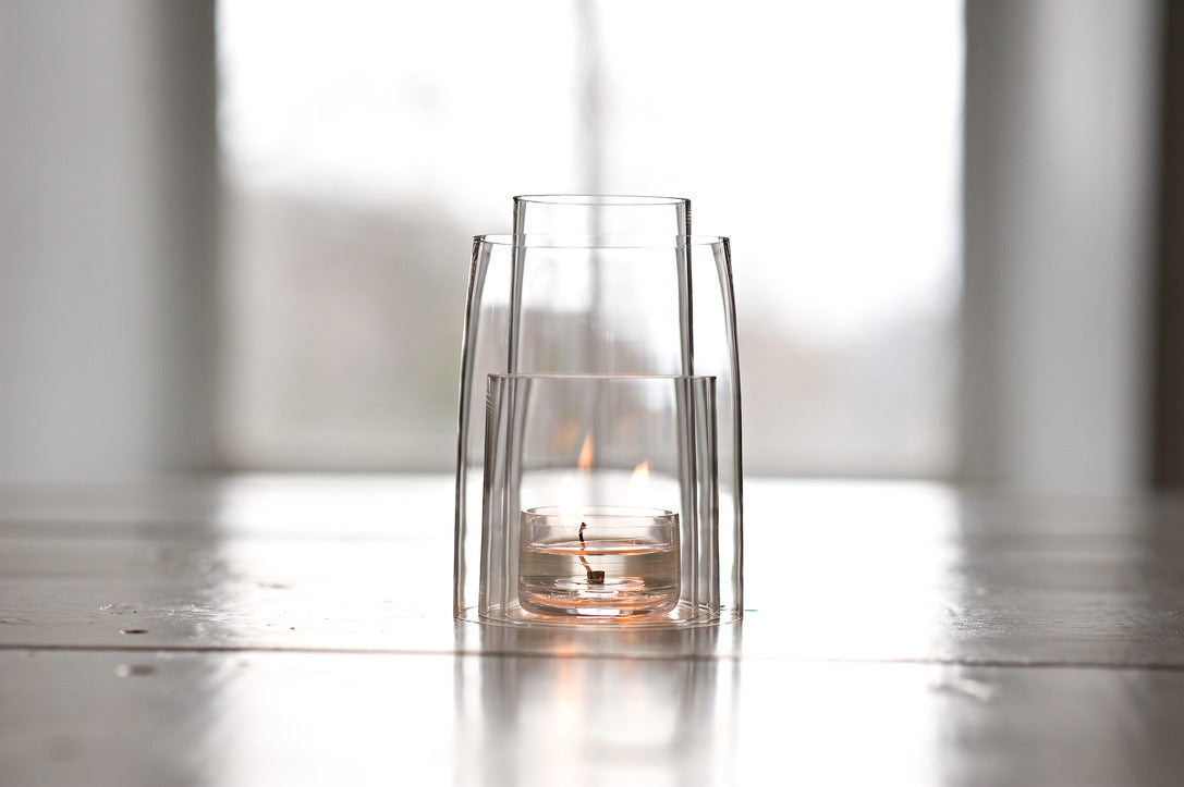 Four pieces of crystal with a clear tea light candle lit on a white table back lit from a depp bright window.