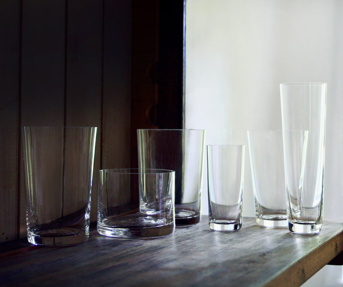 simple crystal glassware in a dark wood vitrine with light from a windowsill