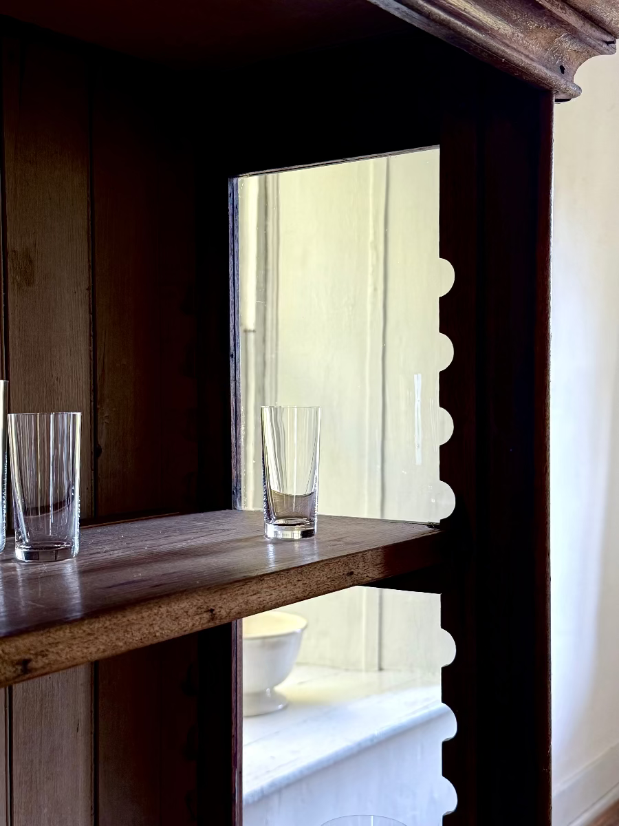 EHRLICH SIMPLE CRYSTAL SHOT GLASS IN DARK WOOD VITRINE IN FRONT OF A DEEP WINDOW