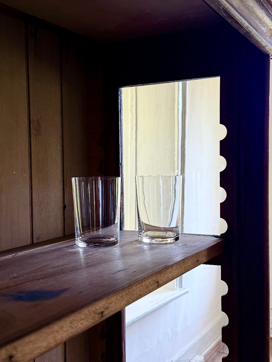 Deborah Ehrlich Simple Crystal Water Glasses in a dark wood vitrine in front of a deep bright window