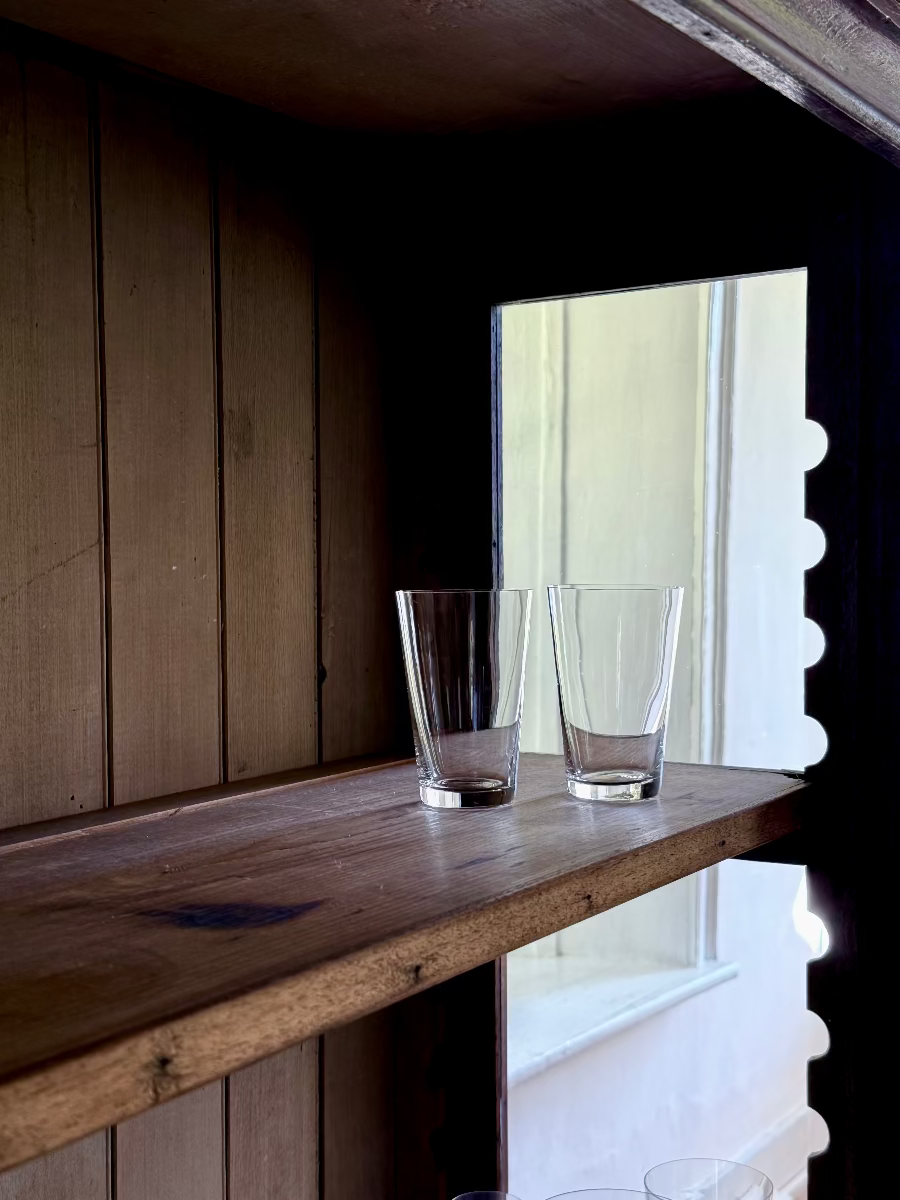 Deborah Ehrlich Simple Crystal White Wine Glasses in a dark wood vitrine in front of a bright deep windowsill