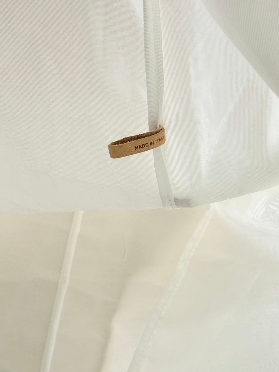 Close-up of a white sailcloth travel bag interior with a small tan leather tag reading 'MADE IN ITALY' attached near a seam.