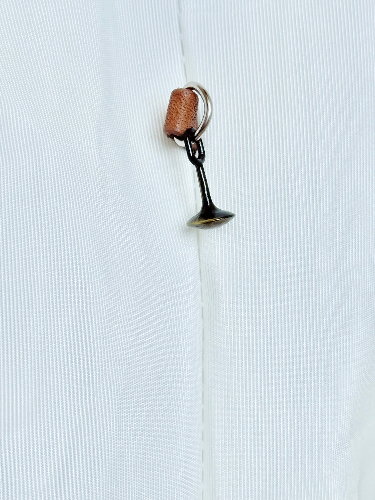 A close-up of a white textured heavyweight sail cloth featuring a cast brass trumpet shaped pull with a small brown leather strap.